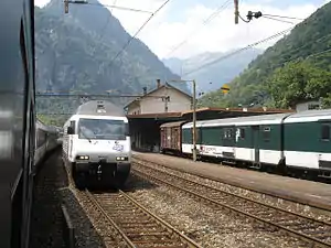 Multiple trains passing a three-story building with gabled roof