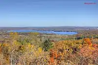 Flat landscape with lake in background and fall-colored orange and yellow trees