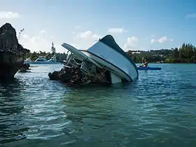 Upended boat resting on rocks near the shore