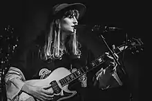 black-and-white image of Faye Webster singing and playing guitar onstage