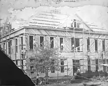 Photography of a two-story building under construction, prominently showing scaffolding and workers posing for the photograph