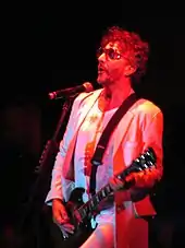 A white man with glasses, wearing a white T-shirt.