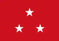 Red flag with three white five-point stars in a centered triange arrangement, peak upward