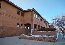 Stone and brick building, with snowy sidewalk in foreground