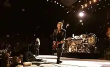 Buckingham onstage playing guitar toward the camera