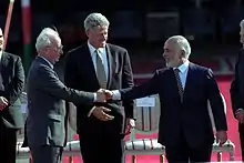 U.S. President Bill Clinton watches Jordan's King Hussein and Israeli Prime Minister Yitzhak Rabin shaking hands, October 1994