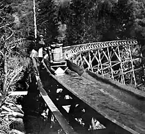 Workers on the catwalk guide a boat over a high trestle.