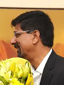 Kris Srikkant smiling while holding a bouquet of flowers