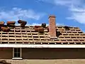 The roof of the commanding officer's quarters receiving new shingles, showing the detail of roof construction.