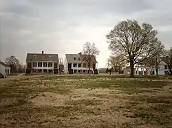 Photograph of the parade ground and surrounding, two-story, white, Army buildings in the early spring.