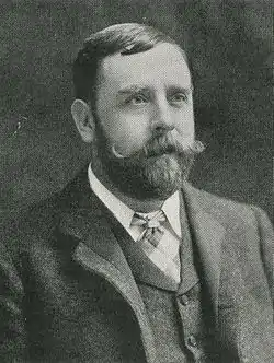 Black and white portrait photograph of a man dressed in Victorian clothing looking slightly off camera without expression