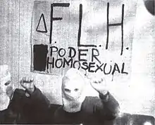 Two hooded FLH members posing and holding a sign