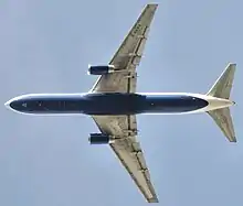 Underside view of a jet in-flight. Each wing of the two wings have an engine. Towards the left are the horizontal stabilizers.