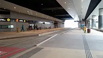 An underground, side platform station with few passengers visible on the platform.