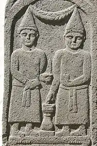 A bas-relief of two men in conic hats and robes