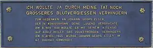 A plaque with the German text in all capital letters:'"Ich wollte ja durch meine Tat noch größeres Blutvergießen verhindern." Zum Gedenken an Johann Georg Elser, der in Königsbronn seine Jugend verbrachte. Am 8. Nov. 1939 wollte er mit seinem Attentat auf Adolf Hitler das Völkermorden verhindern. Am 9. April 1945 wurde Johan Georg Elser im KZ Dachau ermordet.'