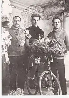 Three men standing with a bicycle