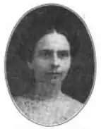 The face of a white woman in an oval frame. Her dark hair is parted center and dressed back away from her face and shoulders.