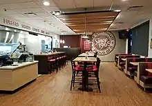 interior of a chili parlor showing tables, counter seating, and open kitchen behind the counter