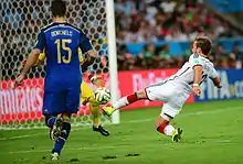 Close-up view from the left of Götze hitting the ball, with the Argentine goalkeeper visible, partly obscured by defender Demichelis