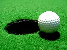 A golf ball next to a hole