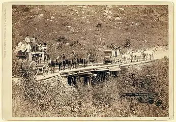 Two large Overland stage wagons on the road to Pierre, South Dakota in 1889. It is the "last official visit of Supreme Court Judges to Deadwood, South Dakota and the first "Legislative Delegation" for the new state of South Dakota