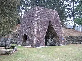 A large stone iron furnace with openings on each of the two sides visible