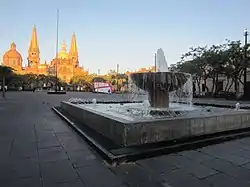 The plaza in 2021; one of the square's fountains is in the foreground and Guadalajara Cathedral is in the background