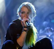 Sandra Nasić squatting on stage with a microphone