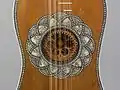 Baroque guitar soundhole with multi-layered parchment rose from behind, surrounded by inlaid rosette (1630).