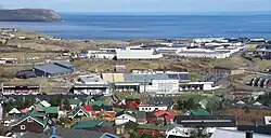 A sports complex surrounded by houses near to the sea.