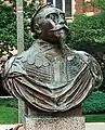 A copper bust of King Gustav Adolph's shoulders and head. He wears his military garb and a crown of laurels. His eyes are fixed at a point in the sky and his chin tilts upward confidently. He wears a full mustache and a triangular goatee. The bust is from Gustavus Adolphus College in Minnesota.