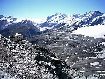 The west side as seen at a distance of 15 km (9.3 mi) from Hörnlihütte, at the foot of the Matterhorn, 3,260 m (10,700 ft) (in the back from left to right): Rimpfischhorn, Strahlhorn, Findelgletscher, Stockhorn (and Gornergrat below it), upper (on the north side) and lower (on the west side) Gornergletscher – the central Monte Rosa massif – Grenzgletscher, Liskamm and several Breithorn peaks on the south side (2008)