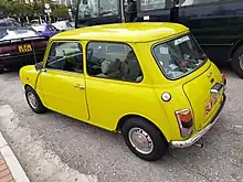 A small yellow car stuck in a traffic jam