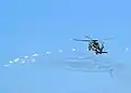 An SH-60B deploys its flares while evasively maneuvering