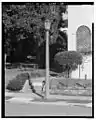 Street lamps are octagonal ornamental metal housings atop hexagonal cast red concrete with granite aggregate columns