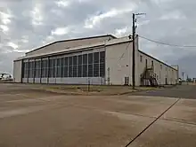 A large tan metal aircraft hanger with two large rollback doors