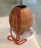 Burnished and Painted Clay Ovoid Vase depicting horned figure, with Round Carnelian Beads in, Burzahom (Kashmir), 2700 BC.