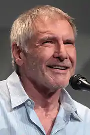 Portrait of a man in blue shirt smiling while talking to a microphone