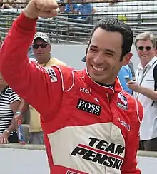 Hélio Castroneves in red and white racing overalls celebrating at the 2009 Indianapolis 500