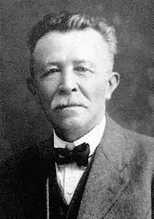 old man with white mustache and full head of hair, wearing bow tie and suit jacket