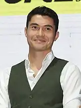 Henry Golding smiles, facing forward