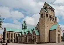 A romanesque stone cathedral, view of the north side. The green copper dome over the transept crossing is visible.