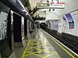 The interior of a building with a rounded ceiling and walls and a white sign hanging from the ceiling reading "Way out Central line"