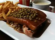 A Quebec-style "hot chicken", topped with green peas.