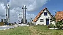 Two large spacecraft next to a v-shaped roof house