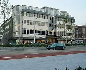 Large five storey building with road and passing car to front