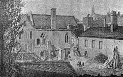 A monochrome illustration of several short buildings clustered in a small space. A yard in the foreground is filled with detritus.