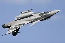  Jet aircraft with centerline external fuel tank during invert flight against blue sky