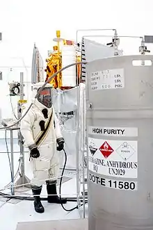 A suited worker looks over the hydrazine fuel supply to be loaded in MESSENGER.